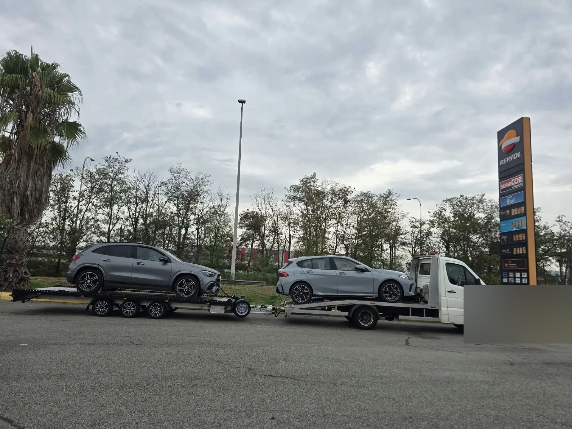 Twee personenauto’s op trailers bij een tankstation