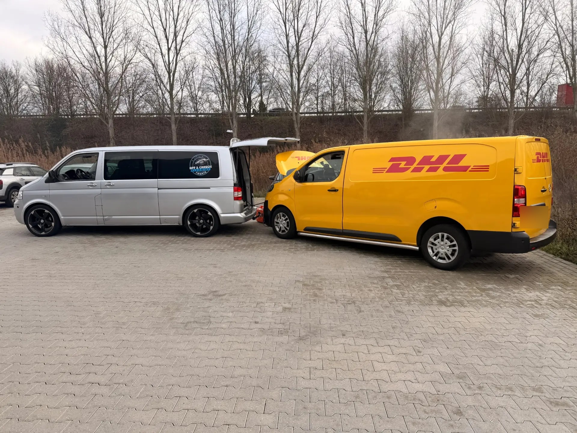 DHL-bestelbus met geopende motorkap tijdens DPF-reiniging en Carbon Cleaning buiten bij de werkplaats in Aadorp